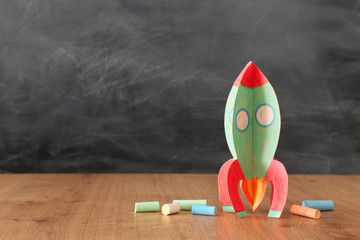 education and back to school concept. cardboard rocket and chalks in front of classroom blackboard