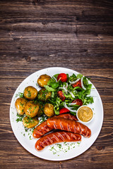 Grilled sausages, baked potatoes and vegetables