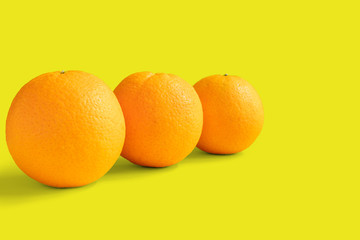 Three navel oranges on yellow background