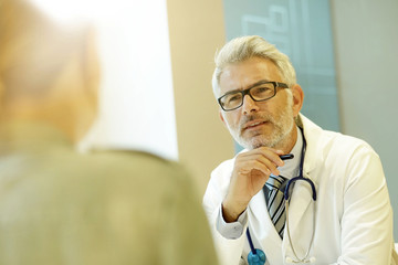 Mature doctor talking to patient in modern clinic