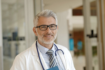 Portrait of mature doctor standing in hospital hallway
