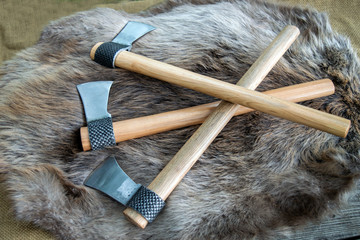 Three throwing tomahawks displayed on a beaver fur with bokeh effect. These hawks are made from a...