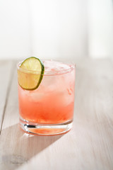 Paloma cocktail served in a tumbler glass. White wooden background, high resolution