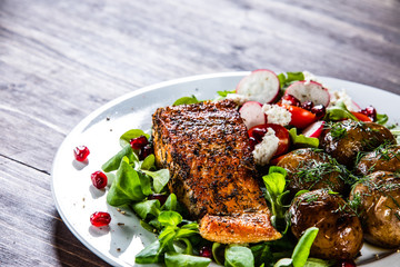 Grilled salmon, baked potatoes and vegetable salad