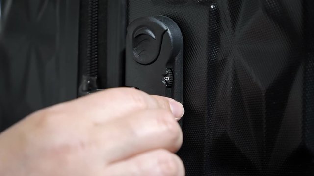 Woman enters the code to open suitcase combination lock on the suitcase and presses the button, hands closeup.