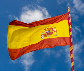 Flag of the Kingdom of Spain, flying by the wind and held by a stick with the same colors, red and yellow