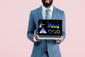 cropped view of smiling african american businessman showing laptop with infographic isolated on blue
