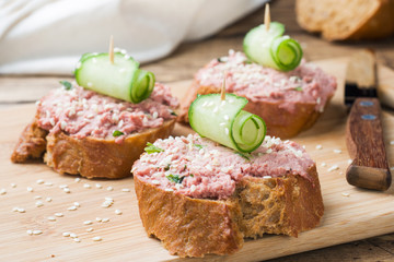 Sandwiches with chicken pate and cucumber on wooden table.