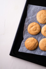 Homemade shortbread cookies on parchment paper in baking tray on wooden white table top view