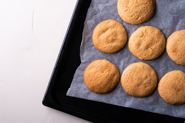 Homemade shortbread cookies on parchment paper in baking tray on wooden white table top view