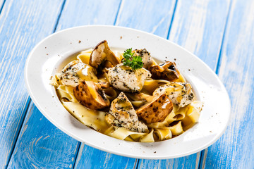 Pasta with chicken and champignon on wooden background