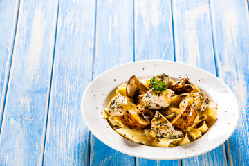Pasta with chicken and champignon on wooden background