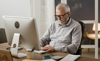 Senior man connecting with his computer at home