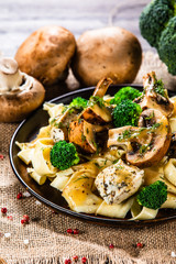 Pasta with chicken and champignon on wooden background