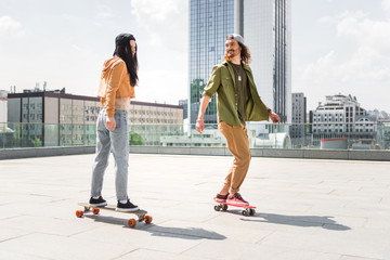 man in casual wear looking at brunette woman, riding on skateboard on roof