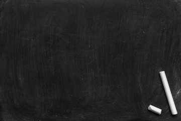 Working place on empty rubbed out on blackboard chalkboard texture background with colorful crayons chalk for classroom or wallpaper, add text message.