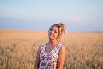 young seductive rural blond hair woman in dress on the yellow wheat field on the sunset