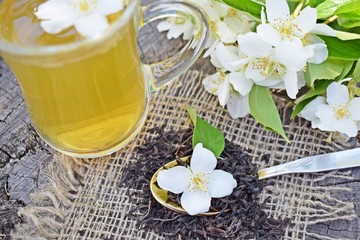 Fototapeta na wymiar Jasmine flowers and fresh tea on wooden background and burlap.