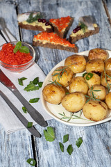 Boiled and roasted young potatoes, red caviar in a transparent scallop, herring sliced.