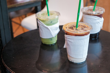 ice coffee and matcha green tea cold drink in takeaway or to go cup on wooden table at cafe