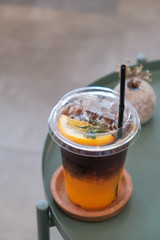 Orange juice in the bottom and dark coffee and  orange slices  on the top in the glass, Ice coffee in coffee shop