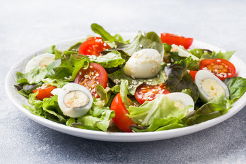 Fresh salad with tomatoes and quail eggs and lettuce.