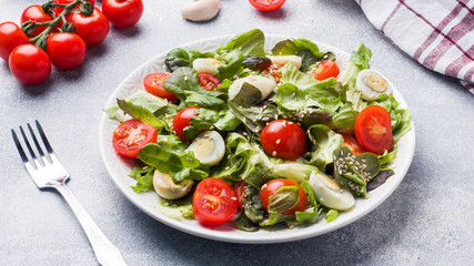 Fresh salad with tomatoes and quail eggs and lettuce.