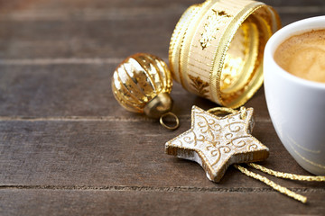 A cup of coffee and a small Christmas Star on wooden background. Close up. 
