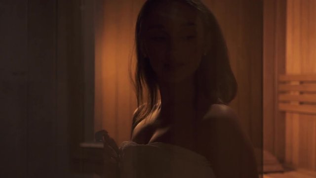 Adult and beautiful woman spending free time in spa salon with modern interior. Beautiful and calm female with brunette hair came in sauna room with glad smile on her charming face