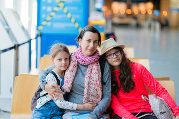 A family of three sitting in a recreation area at the airport