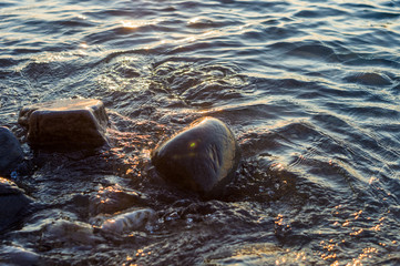 pebble stones on the sea beach, the rolling waves of the sea with foam