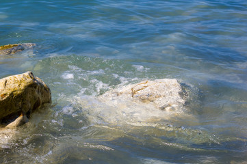 pebble stones on the sea beach, the rolling waves of the sea with foam