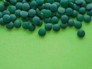 Spirulina algae tablets on green background from top view