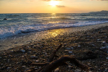Fototapeta premium Amazing sea sunset on the pebble beach, the sun, waves, clouds