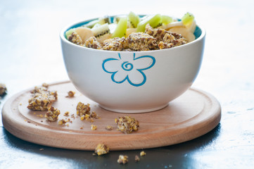 Healthy breakfast of granola, kiwi, banana and yogurt in a bowl on a wooden tray. Fitness diet for weight loss