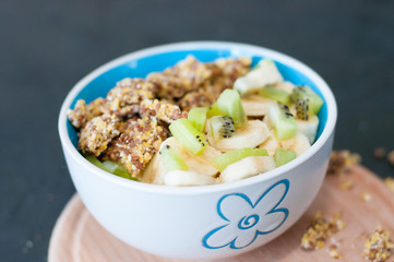 Granola, kiwi, banana and yogurt in a bowl on a wooden stand, dark background. Fitness diet for weight loss and proper nutrition