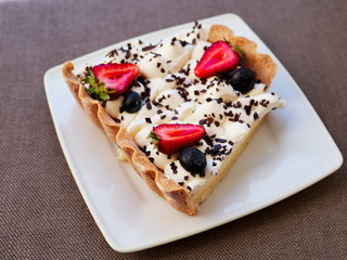 Craft fresh baked delicious strawberry and blueberry cheesecake stacked with cream mousse served on white ceramic plate in cozy city cafe photographed with natural light in warm vintage film colors.