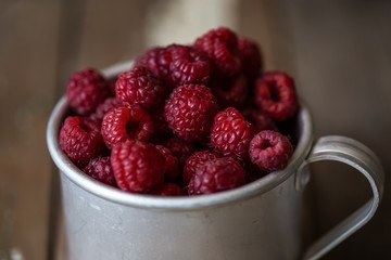 harvest of summer berries. Raspberries in pails on a wooden table.