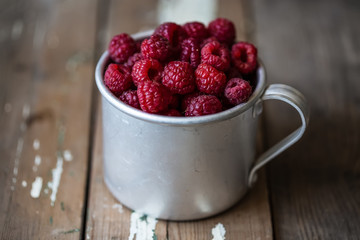 harvest of summer berries. Raspberries in pails on a wooden table.