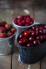 harvest of summer berries. Strawberries, cherries, raspberries in pails on a wooden table. Country style