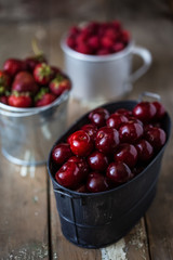 harvest of summer berries. Strawberries, cherries, raspberries in pails on a wooden table. Country style