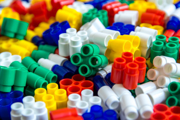 Multicolored plastic building blocks of the designer. Background of plastic colored details building blocks. Parts of bright small spare parts for toys. Close up.