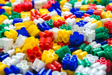 Multicolored plastic building blocks of the designer. Background of plastic colored details building blocks. Parts of bright small spare parts for toys. Close up.