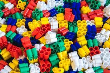 Multicolored plastic building blocks of the designer. Background of plastic colored details building blocks. Parts of bright small spare parts for toys. Top view.