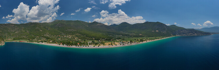 Aerial photo of tropical exotic island bay with beautiful emerald sea and deep blue cloudy sky