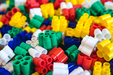 Multicolored plastic building blocks of the designer. Background of plastic colored details building blocks. Parts of bright small spare parts for toys. Close up.