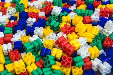 Multicolored plastic building blocks of the designer. Background of plastic colored details building blocks. Parts of bright small spare parts for toys. Close up.
