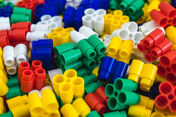 Multicolored plastic building blocks of the designer. Background of plastic colored details building blocks. Parts of bright small spare parts for toys. Close up.