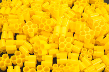 Plastic bricks of yellow color and details of the toy. Yellow background.