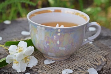 Jasmine flowers and fresh tea on wooden background and burlap.